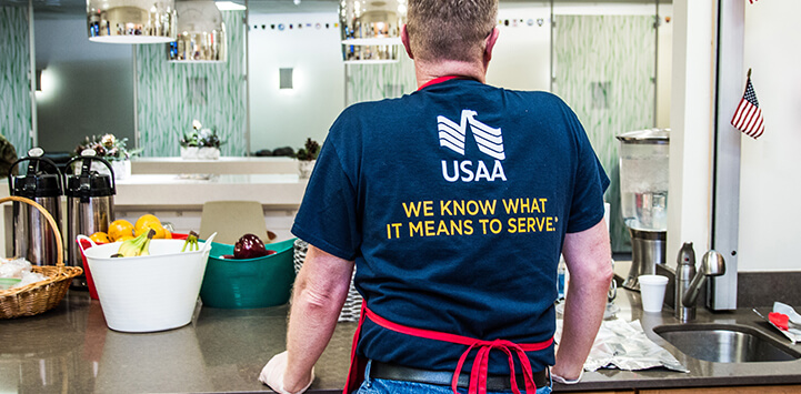 A USAA worker is standing with a shirt that reads 'We know what it means to serve
