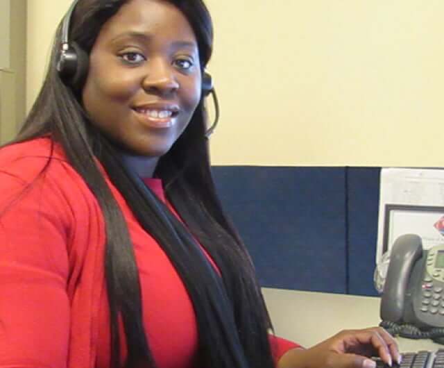Employee at computer wearing a telephone headset.