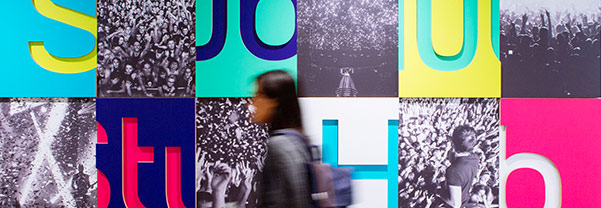An artistic photo of a woman walking next to a wall full of colorful letters