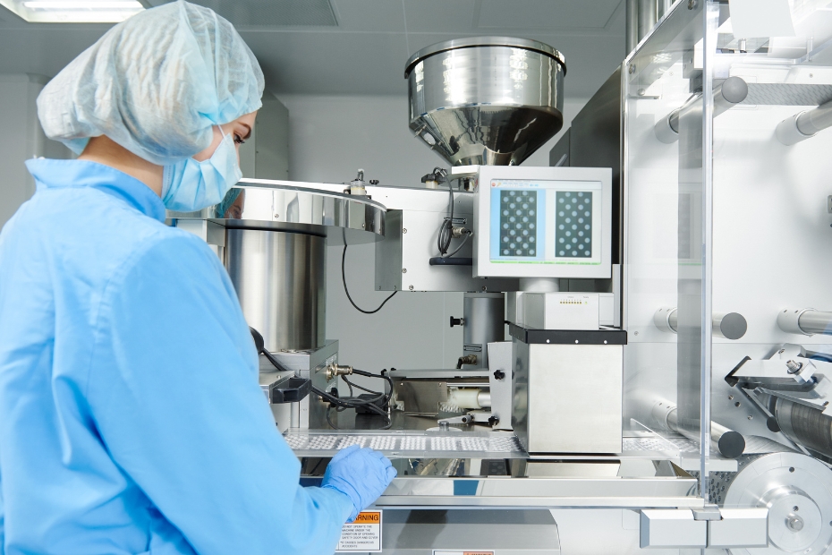 individual in blue medical gown with hairnet on working on equipment