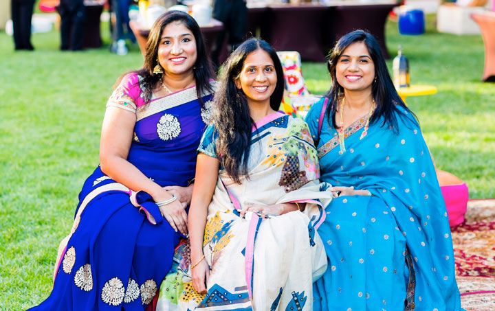 Three women smiling in a park.