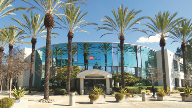 A building with large BD logo sign and palm trees and plant out the front