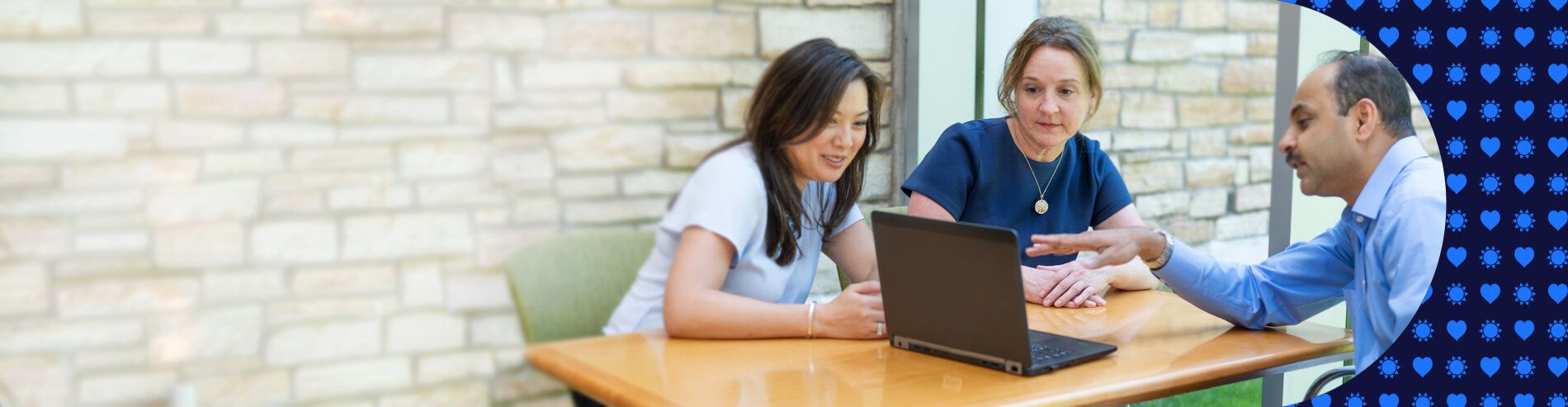 3 persons around table and laptop smiling