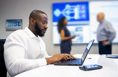 black male employee typing on a laptop in an office conference room