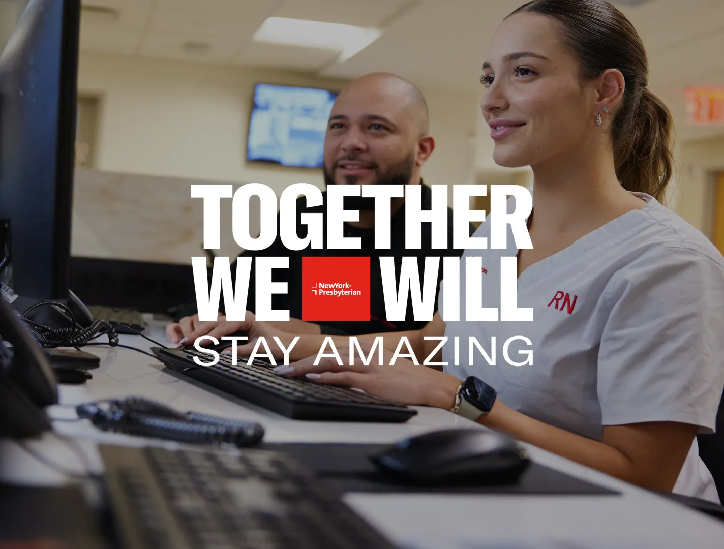 Together We Will Stay Amazing slogan with female and male employee sitting at a desk looking at a computer screen