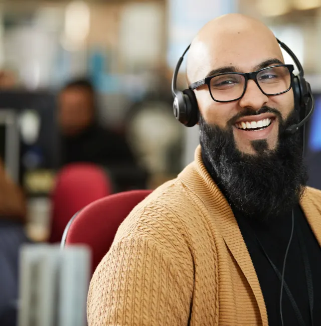 Man wearing tan sweater with a headset on smiling