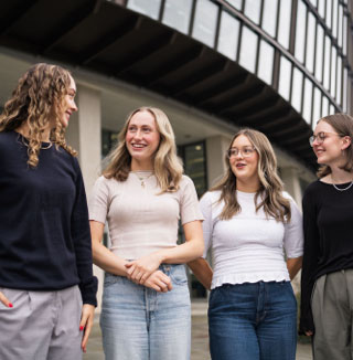 Group of four young adults smiling together