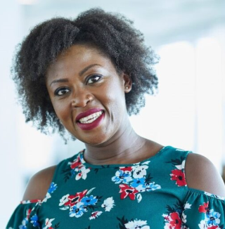 Smiling woman in floral dress with natural curly hair.
