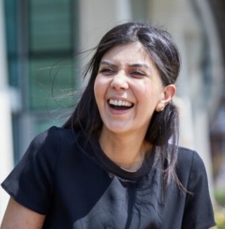 Two women talking and laughing outdoors on a sunny day.