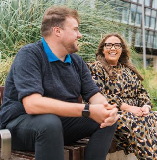 Two colleagues smiling outside office.