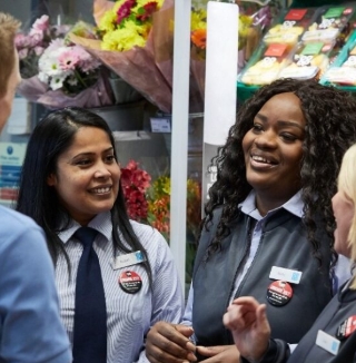 Co-op employees smiling and chatting near flower section.