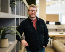 Man in glasses leaning on office shelf