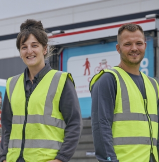 Three workers in safety vests standing outside.