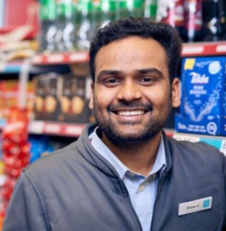 Smiling man standing in front of grocery store shelves.