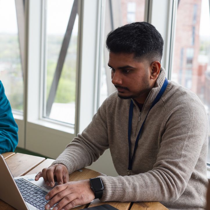 Two men working on laptops in a bright office.
