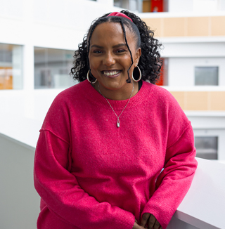 Smiling woman in pink sweater standing in office.