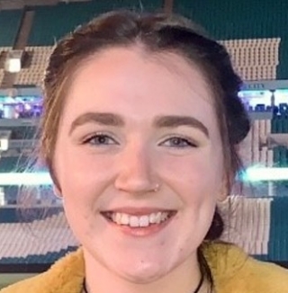 Smiling woman in a stadium with bright lights behind.