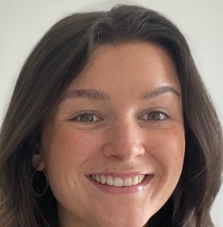 Smiling woman in white room, wearing hoop earrings.
