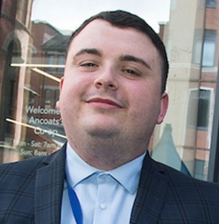 Man in suit standing outside Co-op store entrance.