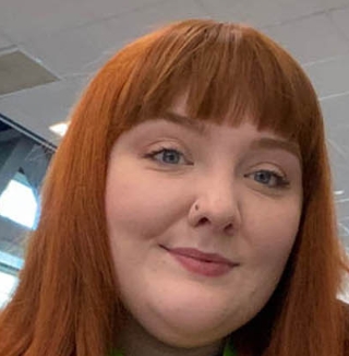 Woman with red hair smiling at her office desk.
