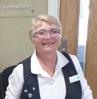 Smiling woman at reception desk in funeral home.