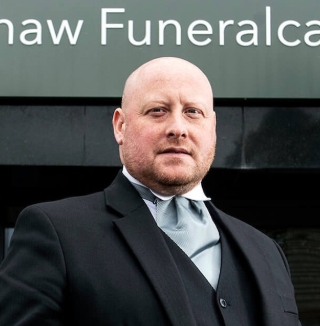 Man in suit standing outside Wishaw Funeralcare.
