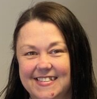 Smiling woman in office with photo collage behind her.