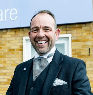 Smiling man outside Co-op Funeralcare building.