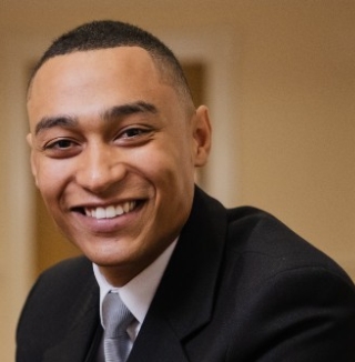 Smiling man in suit sitting in hallway.