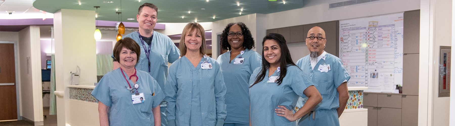 A team of 6 Northwestern Medicine respiratory therapists smiling for a photo together, all wearing light blue scrubs.