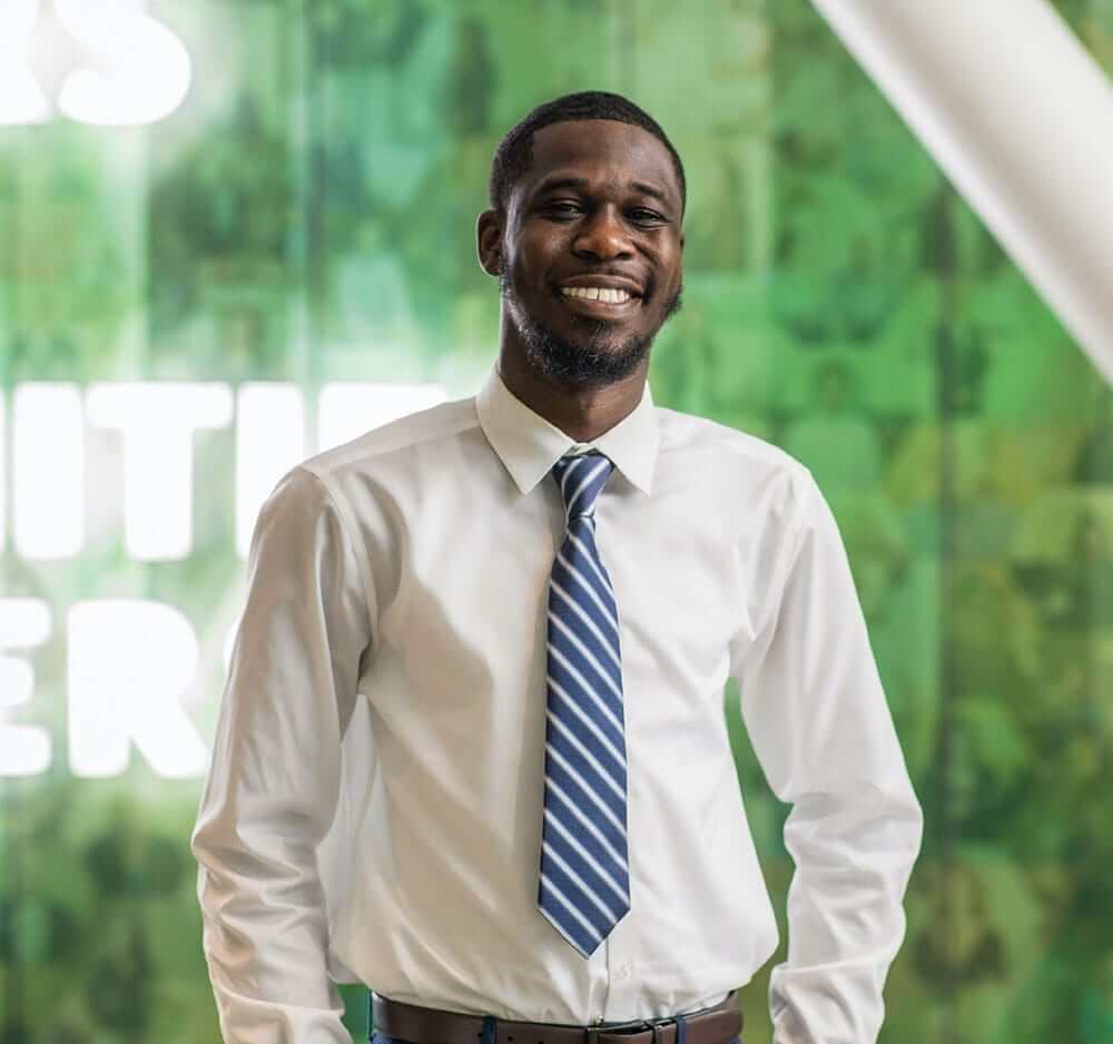 young black male employee wearing a white shirt and tie and smiling