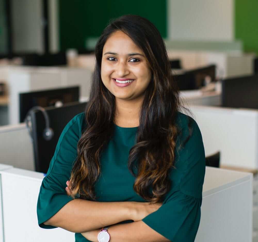 Indian female employee standing and smiling inside an office