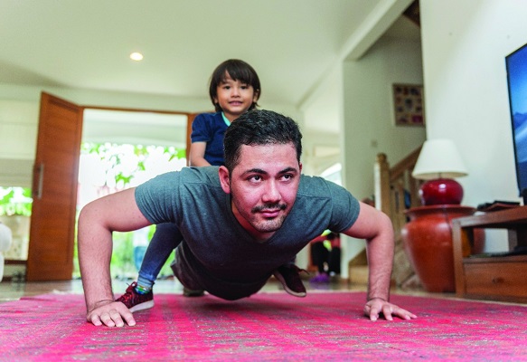 Man doing push-up with child on his back