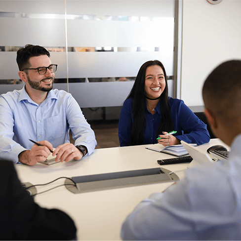Smiling employees seated around a conference table.