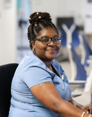 Female nursing assistant smiles in a Duke Health hallway.