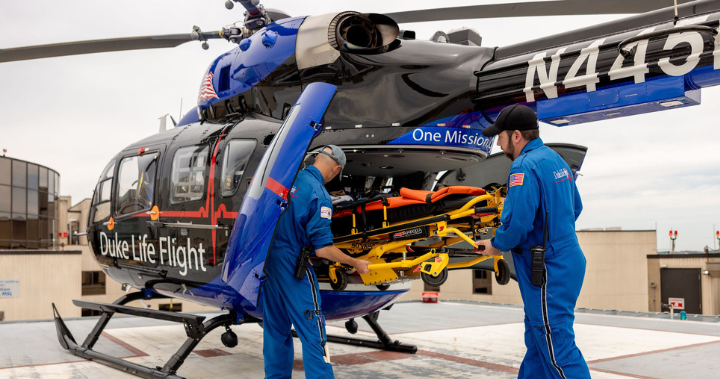 duke life flight helicopter and two team members placing equipment inside