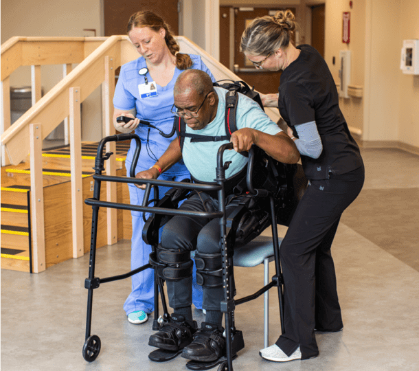 Two nurses helping an elderly person walk again.