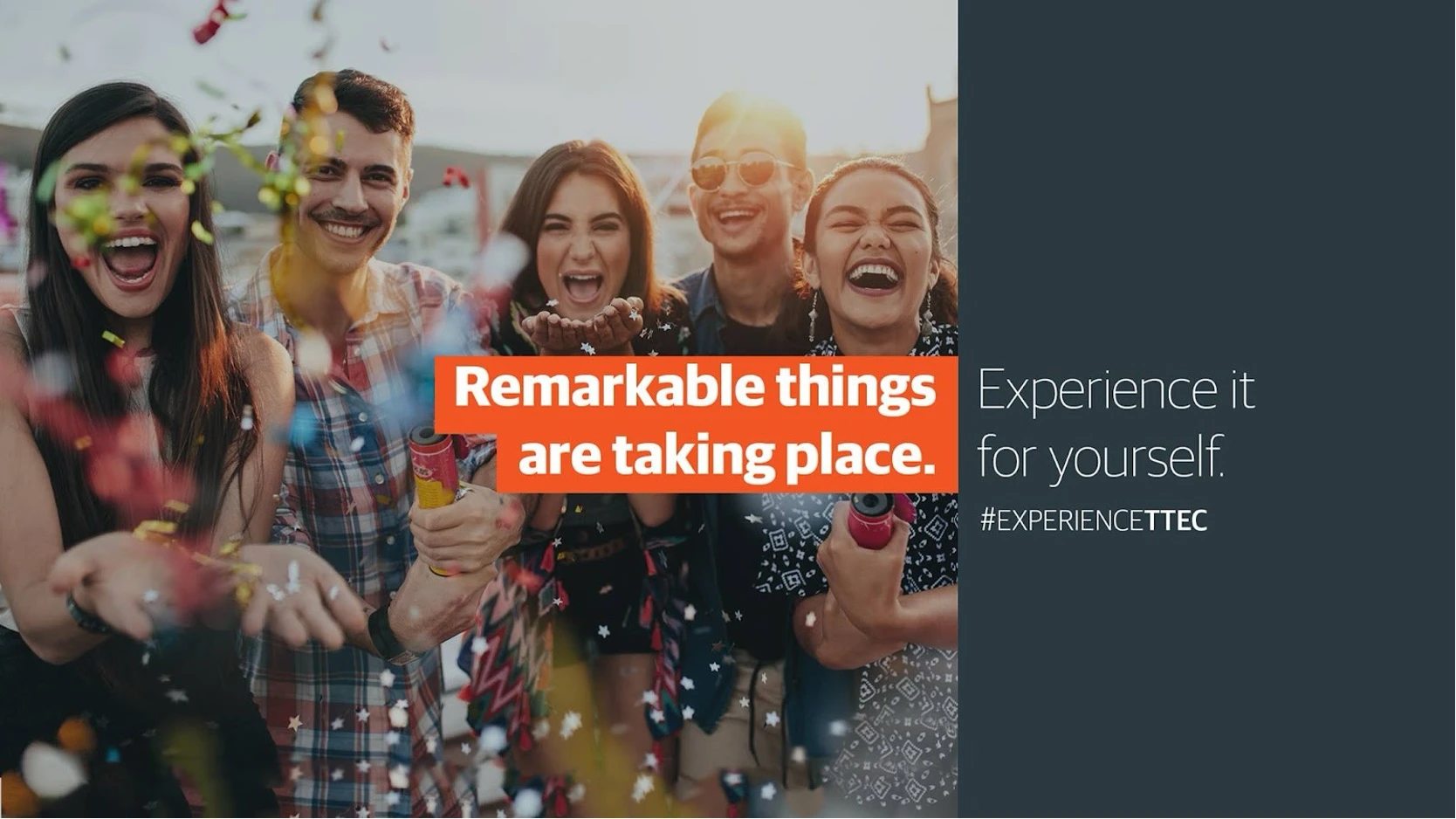 Five young adults are joyfully celebrating outdoors as confetti falls around them. They are smiling and laughing, some with their mouths open in excitement.