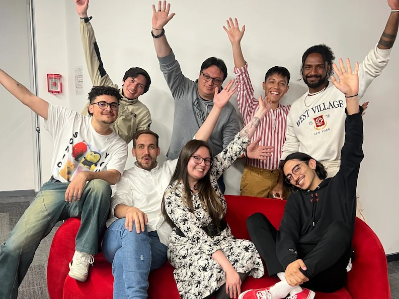 A team from TTEC Mexico posing happily for picture with their hands up.