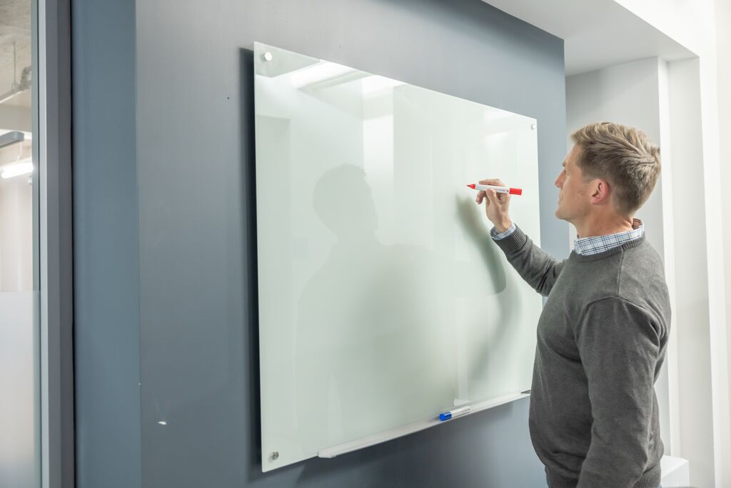 Man writing on white board during a sales meeting
