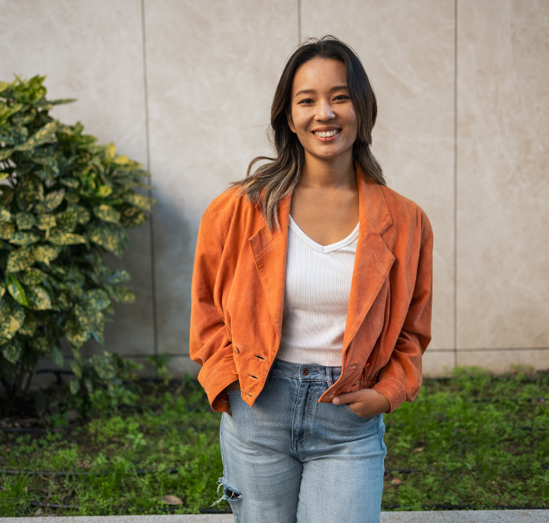 Girl wearing an orange cardigan with a white shirt smiling