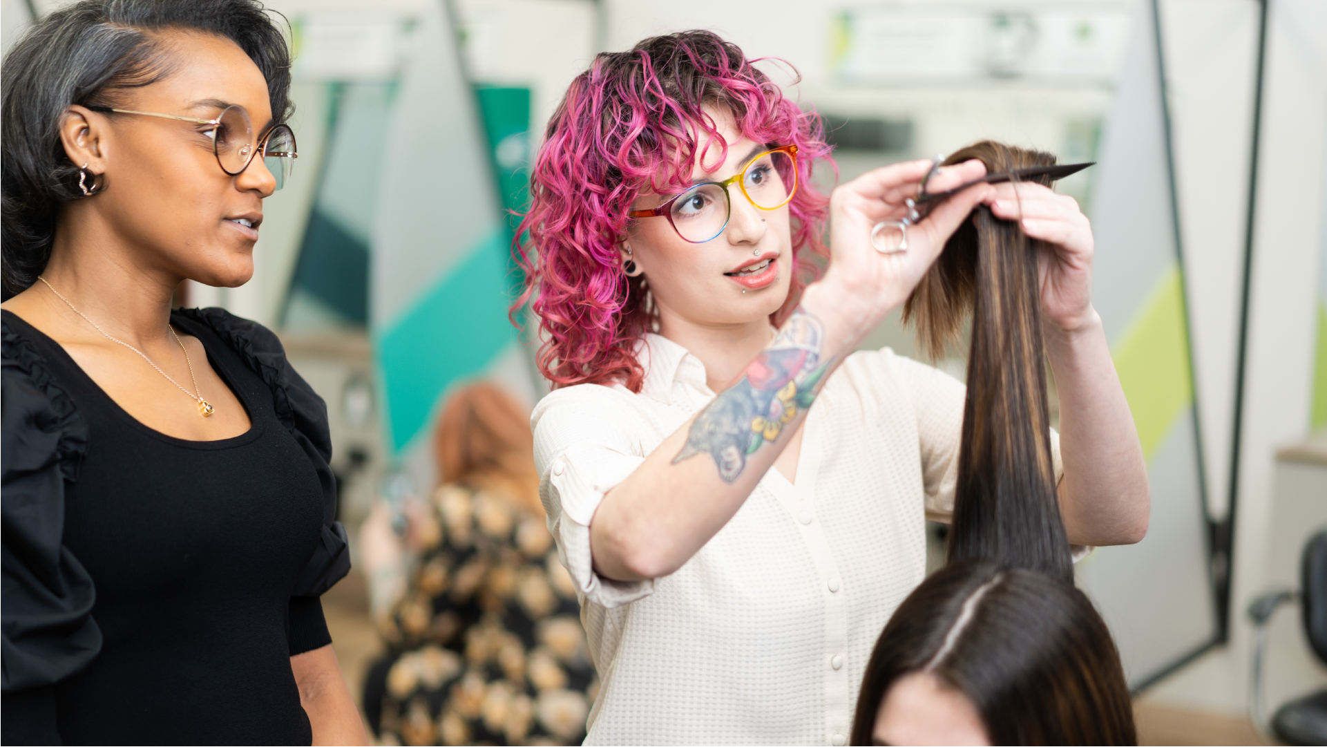 New stylist cutting a long layered haircut while an experienced stylist observes
