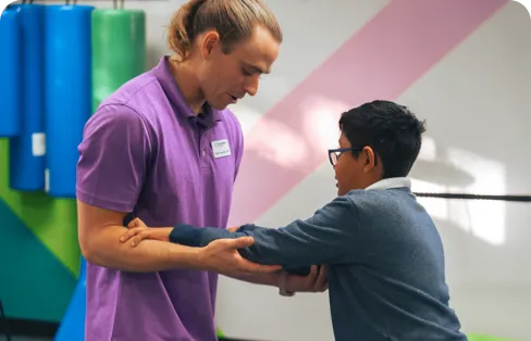 A person assists another person by holding their arms.