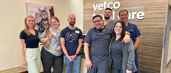 Smiling veterinary team standing together indoors.