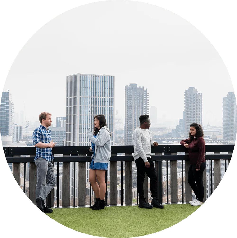 People chatting on a rooftop with city views.