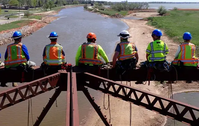 employees with hardhats sitting on medal rafters