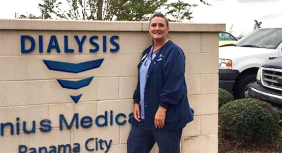 Female nurse standing in front of Fresenius Medical Dialysis sign