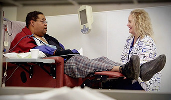 A doctor speaking with a patient who is in a chair