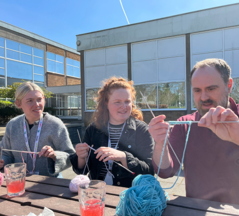 Three team members learning how to knit