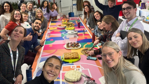 team members posing for a photo in front of a table of treats baked by the team